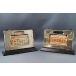 Two silver engine turned mounted desk calendars, both with associated incomplete date cards,