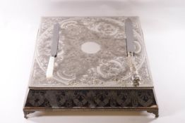A silver plated wedding cake stand, profusely engraved with related motifs, 45cm square,