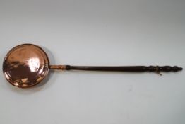 A 19th century copper warming pan with turned handle