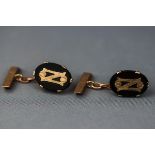 A yellow gold set of cufflinks having an oval onyx terminal with fixed initial decoration.