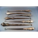 Seven button hooks each with silver handles, four embossed with C scrolls and foliage,