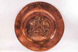 A circular copper wall plate, hammered in relief with a ship in full sail, marked 'T H', 36.