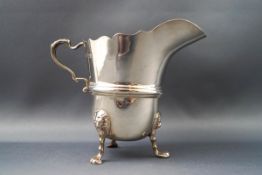 A silver milk jug, with double scroll handle standing on three cast lion mask and paw feet,