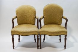 A pair of 19th century mahogany armchairs with scroll arms and shaped seats on tapering fluted legs,