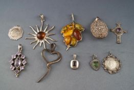 A selection or sterling silver pendants consisting of : Large amber leaf, Large amber sun, cross,