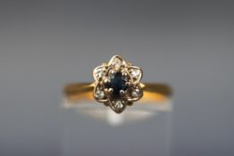 A yellow gold flower cluster ring set with a central round sapphire and six round brilliant