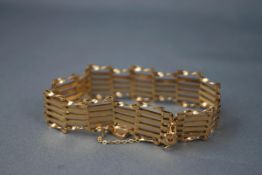 A yellow gold six bar gate bracelet, twisted and plain. Padlock and safety chain.