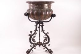 A circular copper jardiniere with gadrooned body and stylised flower design, on wrought iron stand,