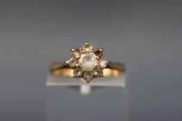 A yellow gold cluster ring set with nine round cut white sapphires.