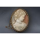 A yellow gold brooch consisting of a large oval cameo carved as a classical female design.