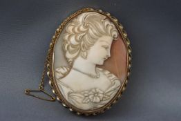 A yellow gold brooch consisting of a large oval cameo carved as a classical female design.