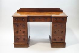 A Victorian mahogany inverted breakfront pedestal desk with an arrangement of nine drawers,