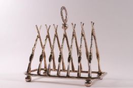 A large silver plated toast rack modelled as crossed rifles with a wreath holder,