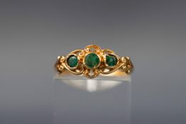 A yellow gold dress ring set with three round emeralds.