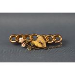 A yellow gold bar brooch of abstract padlock and leaf design.