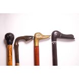 A Country walking stick with carved horn hoof handle, a brass duck's head walking stick,