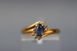 A yellow gold abstract cluster ring set with an oval sapphire and eight round brilliant diamonds.