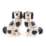 A pair of Staffordshire pottery black and white spaniels with gilt painted chains,