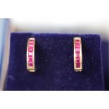 A yellow gold pair of hoop stud earrings each set with six square rubies.