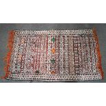 A Moroccan flat weave kelim with diamond pattern and metal sequins on a red ground,