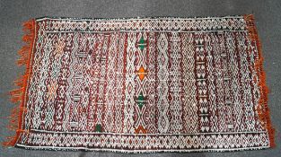 A Moroccan flat weave kelim with diamond pattern and metal sequins on a red ground,