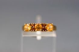 A yellow gold half hoop ring set with orange and yellow topaz stones.