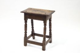 An 18th century oak joint stool with plank top, turned and block legs,