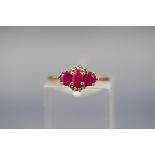 A yellow gold ring set with three oval rubies and twelve variable single cut diamonds.