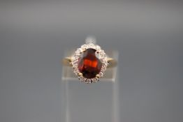 An 18ct gold, garnet and diamond oval cluster ring,