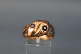 A yellow gold double snake ring set with one ruby and one garnet. Rose shoulders/shank.