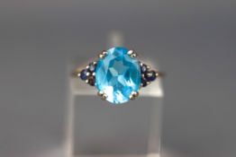 A white gold dress ring set with an oval blue topaz and six round cut sapphires.