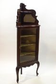 An Edwardian mahogany corner cabinet with carved decoration and mirror back,