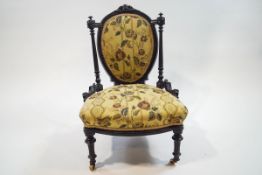A Victorian ebonised nursing chair on turned supports,