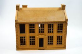 A dolls house in the form of a Georgian residence with four windows above a central door,