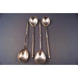 A set of four Russian white metal spoons with spirally fluted handles and engraved bowls,