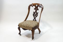 A Victorian rosewood nursing chair with heavily carved and pierced splat on shaped seat and
