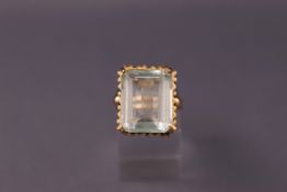 A yellow metal dress ring set with a rectangular faceted low commercial quality aquamarine.