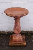 A re-constituted stone bird bath with terracotta finish,