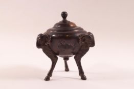 A 19th century bronze Classical inkwell and cover, the three feet as rams heads and legs,