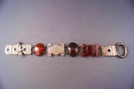 A silver Scottish bracelet stylized as a belt with cut agate links and engraved finish.