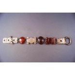 A silver Scottish bracelet stylized as a belt with cut agate links and engraved finish.