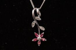 A white metal flower pendant set with pink tourmaline and diamonds.