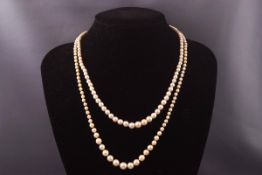 Two strands of graduated cultured pearl necklaces each having silver clasps set with