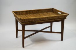 A bamboo two handled tray on an oak luggage stand,