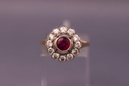 A 1950's ruby and diamond cluster ring, centred with a round mixed-cut ruby approx 0.
