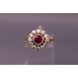 A 1950's ruby and diamond cluster ring, centred with a round mixed-cut ruby approx 0.