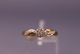 A yellow and white metal ring set with a single diamond and diamond shoulders. Shank stamped DIA .