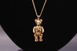 A yellow gold articulated gem set teddy bear pendant on 9ct gold chain. Gross weight: 8.