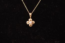 A yellow metal flower pendant set with a 0.01ct single cut diamond.