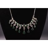 A white metal centrepiece necklace set with pear cut emeralds and single cut diamonds.